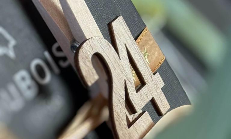 Adventskalender von DuBois et fils: Bild von der Nummer 24 an einem Geschenkpaket mit einer Uhr drin.